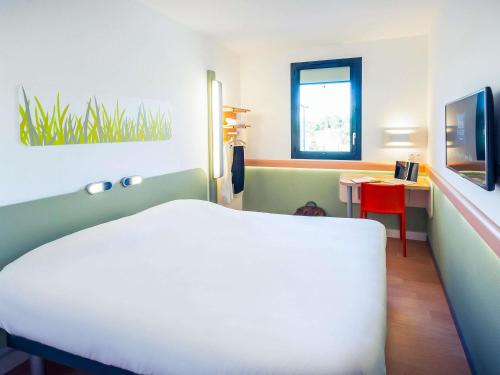 a bedroom with a white bed and a red table at ibis budget Troyes Est in Saint-Parres-aux-Tertres