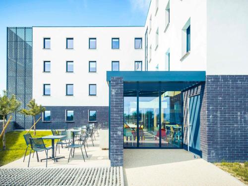 a building with a patio with tables and chairs at ibis budget Troyes Est in Saint-Parres-aux-Tertres