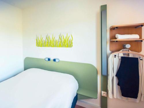 a bedroom with a bed and a plant on the wall at ibis budget Troyes Est in Saint-Parres-aux-Tertres