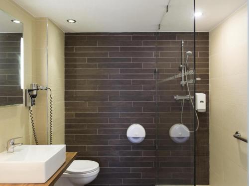 a bathroom with a shower and a toilet and a sink at Ibis Styles La Louvière in La Louvière