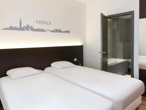 two beds in a room with a sign on the wall at Ibis Styles La Louvière in La Louvière
