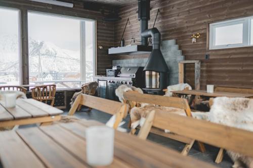 a dining room with tables and chairs and a stove at Mefjord Brygge in Mefjordvær