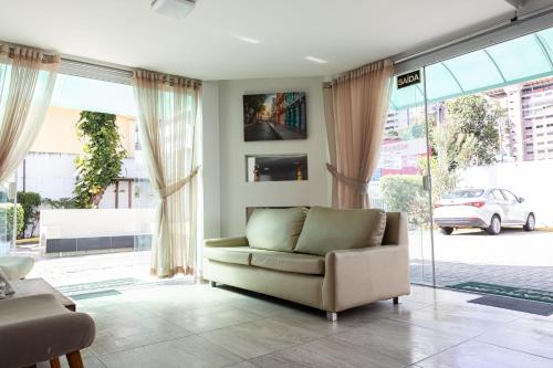 a living room with a couch and large windows at Scenarium Hotel in Recife