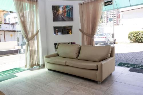 a living room with a couch in front of a window at Scenarium Hotel in Recife