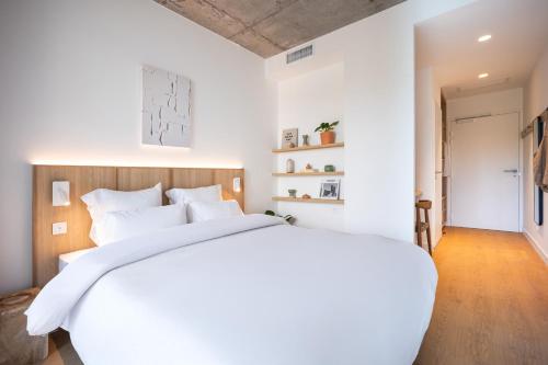 a white bedroom with a large bed with white pillows at Babel Community Hôtel Lille - Villeneuve d'Ascq in Villeneuve d'Ascq
