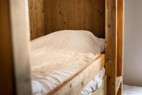 a wooden bunk bed with white sheets on it at Gite à la ferme, authentique & accessible PMR 