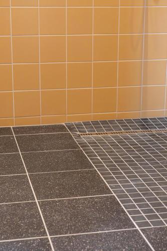 an empty bathroom with orange and gray tiles at Gite à la ferme, authentique & accessible PMR 