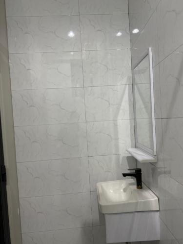 Un baño blanco con lavabo y espejo. en King luxury bedroom, en Dar es Salaam