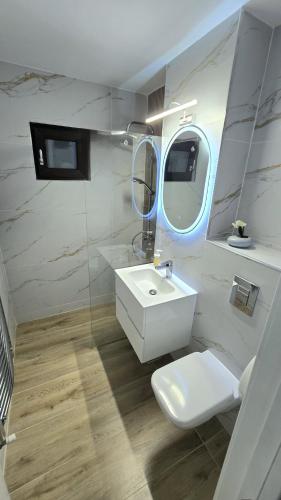 a bathroom with a sink and a toilet and a mirror at Ultracentral Luxury in Piteşti