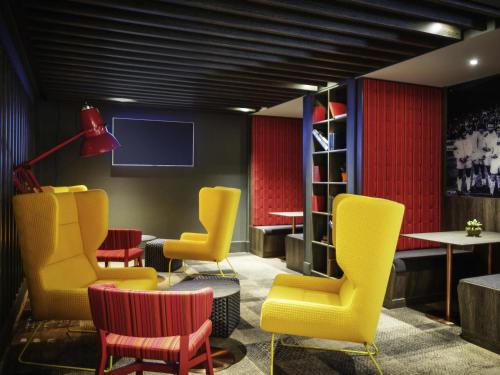 a room with yellow chairs and a tv at ibis Styles Leeds City Centre Arena in Leeds