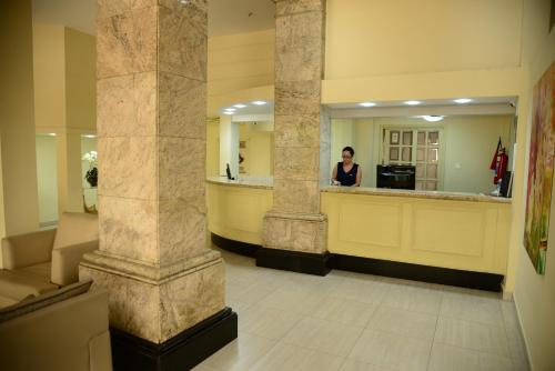 a woman standing at a counter in a lobby at River Park Hotel in Resende