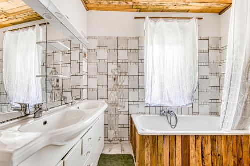 a bathroom with a tub and a sink and a tubermottermott at Maison de Vacances d'Amélie in Saint-Germain-dʼEsteuil
