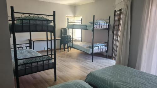 a room with three bunk beds and a table at Bedrock Backpackers in Harrismith