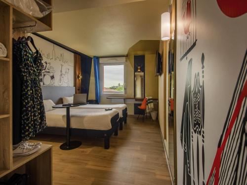 a hotel room with two beds and a desk at Ibis Styles Toulouse Blagnac Aéroport in Blagnac