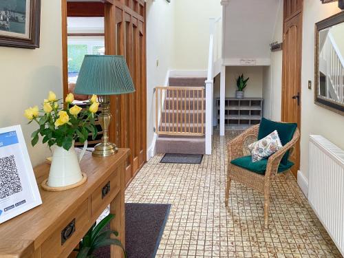 a hallway with a chair and a desk with a lamp at Linnets in Fitzhead