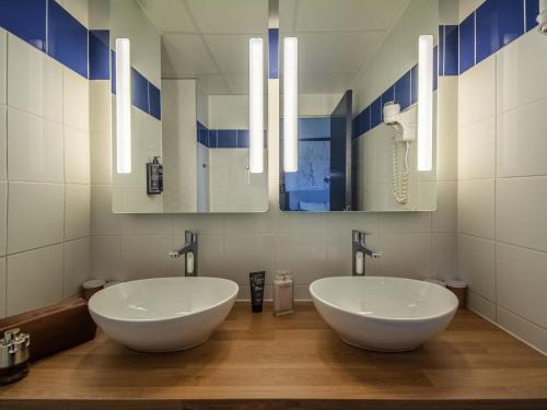 a bathroom with two white sinks and a mirror at Ibis Styles Toulouse Blagnac Aéroport in Blagnac