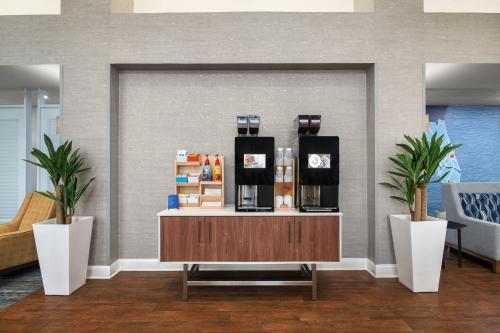 a lobby with a coffee shop with two potted plants at Holiday Inn Express & Suites Destin - Miramar Beach by IHG in Destin