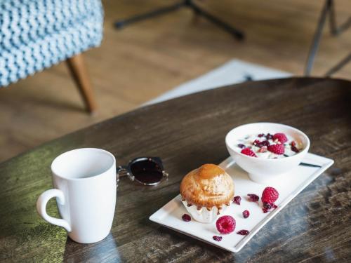 a table with a plate of food and a cup of coffee at Ibis Styles Toulouse Blagnac Aéroport in Blagnac