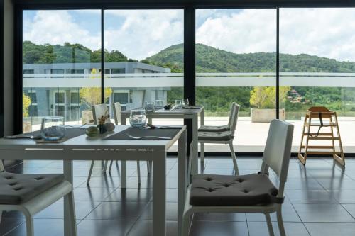 a dining room with a table and chairs and a large window at 九雅集 The Nine Refined Retreats in Rawai Beach