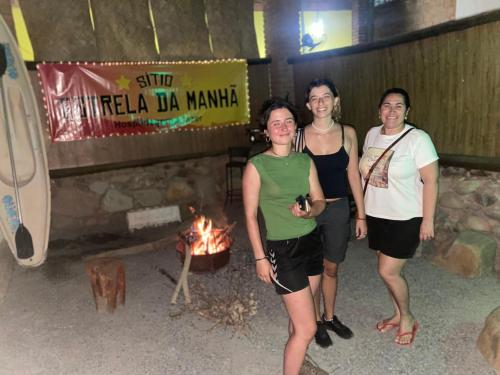 a group of three people standing in front of a fireplace at Sítio Estrela da Manhã Hospedagem e Lazer in Palmeiras