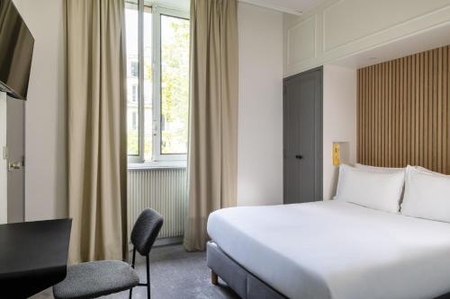 a hotel room with a bed and a desk and a window at Hôtel Korner Châtelet in Paris