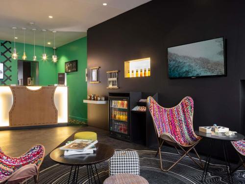 Un salón con sillas, una mesa y una estantería. en Ibis Styles Paris Gare Saint Lazare, en París