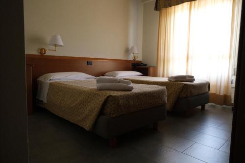 two beds in a hotel room with a window at Albergo Zoello Je Suis in Castelvetro di Modena