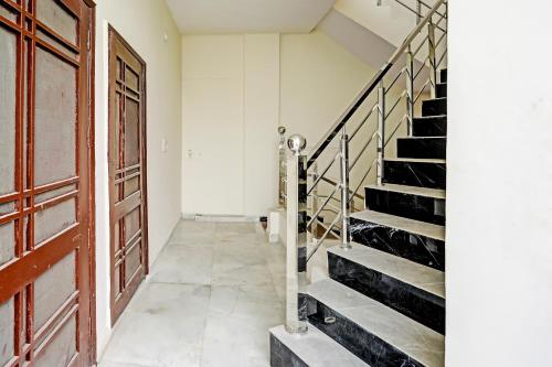 a hallway with a wooden door and stairs at Hotel O The Happy Homestay in Morādābād