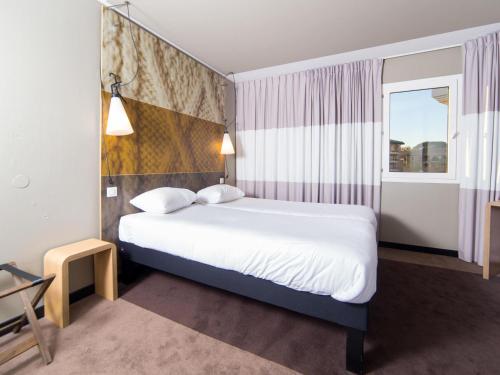 a hotel room with a bed and a window at Ibis Toulouse Purpan Aeroport in Toulouse