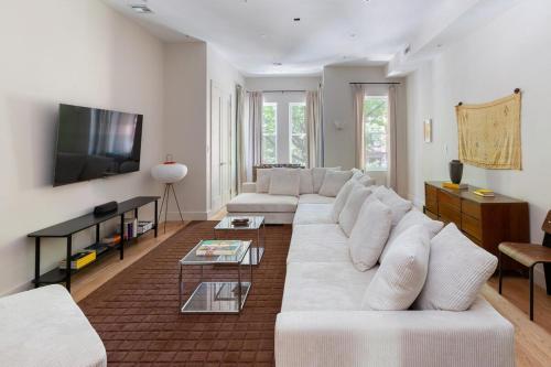 a living room with a white couch and a tv at Massive NYC Brownstone with Patio in New York