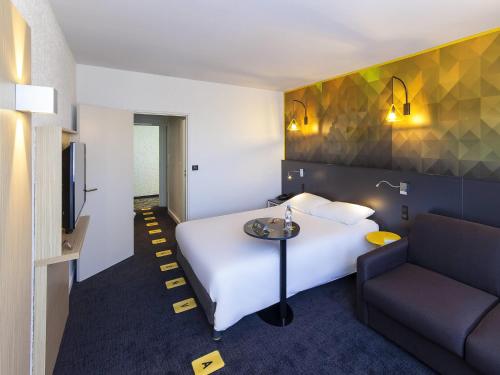 a hotel room with a bed and a couch at ibis Styles Poitiers Nord in Poitiers
