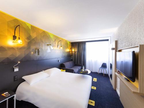 a hotel room with a white bed and a tv at ibis Styles Poitiers Nord in Poitiers