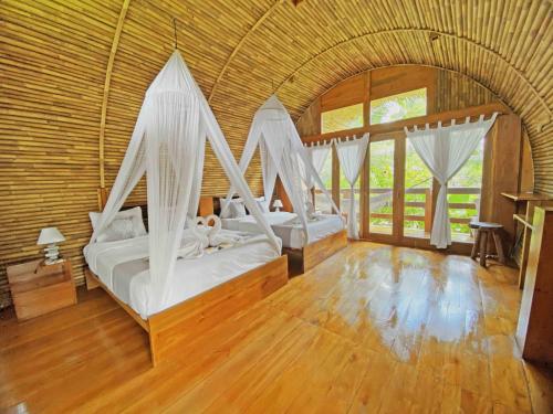 a bedroom with two beds with drapes at Lagoona Beach Bungalows - Eco Bungalows Batukaras in Batukaras