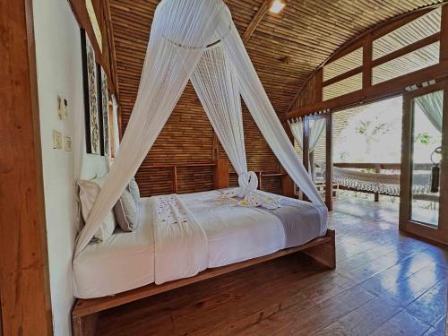 a bedroom with a bed with mosquito net at Lagoona Beach Bungalows - Eco Bungalows Batukaras in Batukaras