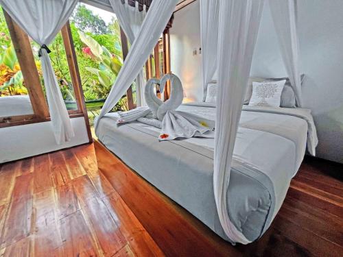 a bedroom with two beds with white drapes at Lagoona Beach Bungalows - Eco Bungalows Batukaras in Batukaras