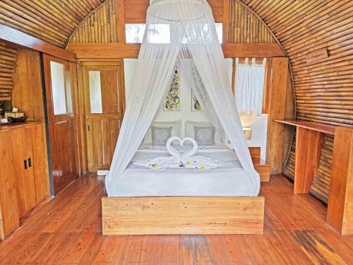 a bed with a canopy in a room at Lagoona Beach Bungalows - Eco Bungalows Batukaras in Batukaras