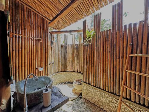 a bathroom with a wooden wall with a tub at Lagoona Beach Bungalows - Eco Bungalows Batukaras in Batukaras