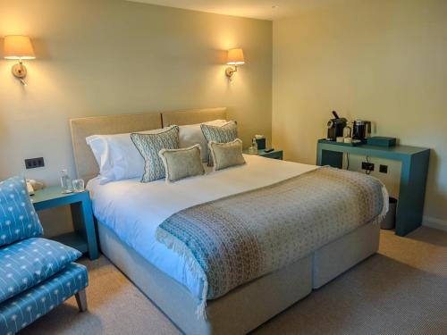 a bedroom with a large bed and a blue chair at House of George W Davies in Broadway