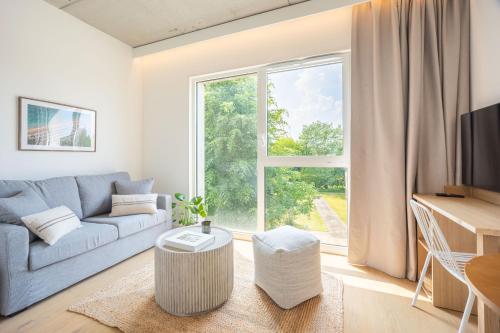 a living room with a blue couch and a large window at Babel Community Hôtel Lille - Villeneuve d'Ascq in Villeneuve d'Ascq