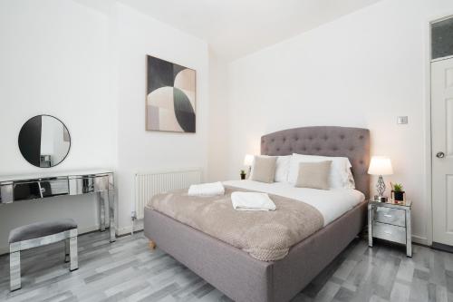 a white bedroom with a large bed and a chair at Newly Renovated 4BR House with lots of amenities in Liverpool