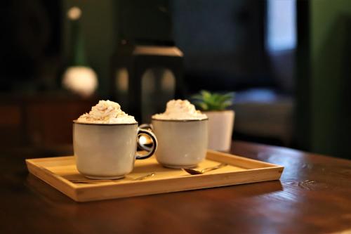 two coffee cups with whipped cream on a wooden table at Átkapcsol-LAK Vendégház in Csókakő