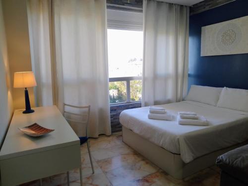 a bedroom with a bed and a table and a window at Studio with views, gardens and pool in Torremolinos