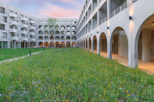 an empty courtyard of a building with a field of flowers at Babel Community Hôtel Lille - Villeneuve d'Ascq in Villeneuve d'Ascq