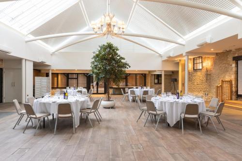 a banquet hall with white tables and chairs and a chandelier at voco Oxford Thames by IHG in Oxford