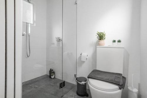 a white bathroom with a toilet and a shower at Pyrmont NSW - 3 Bedroom Apartment- 8 Guests - NetFlix in Sydney