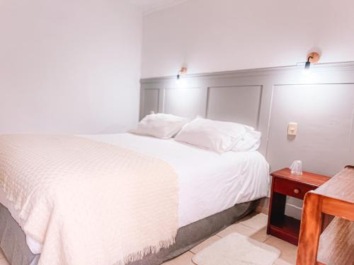 a bedroom with a white bed and a wooden table at Hostal del Rio Talca in Talca