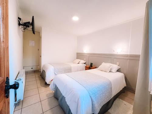 two beds in a room with white walls at Hostal del Rio Talca in Talca