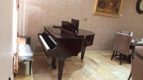 a piano in a room with a table and chairs at Reina Villa Hotel in Benin City