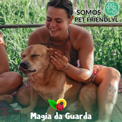 Una mujer está sentada junto a un perro. en Pousada Magia da Guarda, en Palhoça