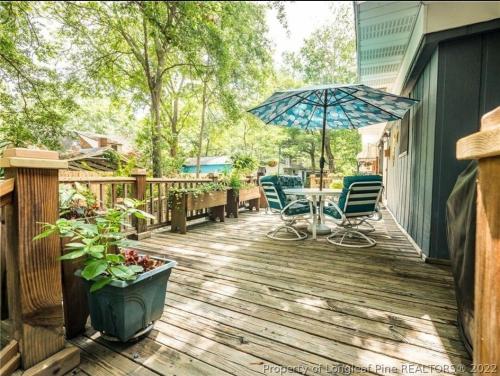 a wooden deck with a table and an umbrella at Central located large home on quiet wooded street in Lumberton